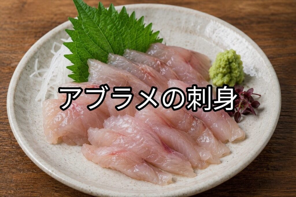 白い皿に盛り付けたアブラメの刺身。大葉、薬味、わさびを添えた新鮮な刺身料理。