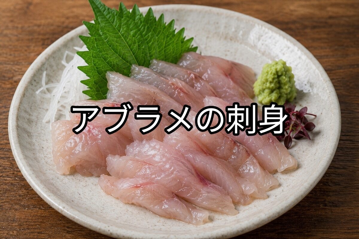 白い皿に盛り付けたアブラメの刺身。大葉、薬味、わさびを添えた新鮮な刺身料理。