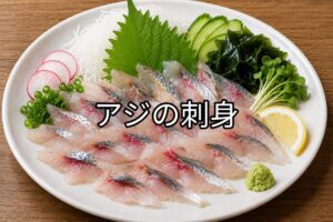 アジの刺身を白い皿に盛り付けた料理写真。大葉・大根のつま・わかめ・きゅうり・レモン・わさびを添えて彩りよく仕上げている。