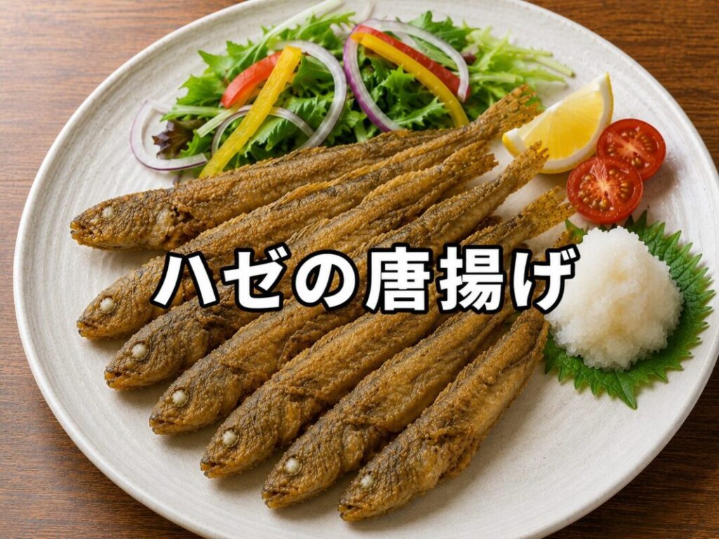 白い皿にハゼの唐揚げを複数匹盛り付け、サラダ、レモン、大根おろし、ミニトマトを添えた料理画像