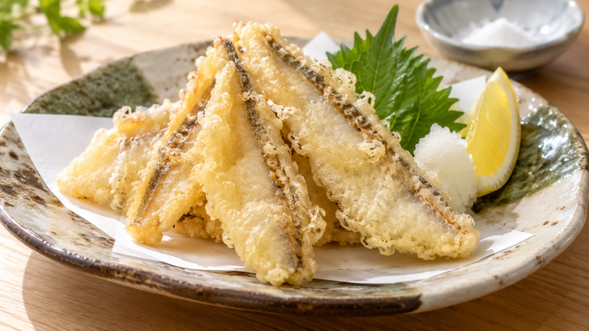 三枚おろしにしたベラの白身を薄い衣で揚げ、大葉の天ぷら、レモン、大根おろしと盛り付けた料理写真