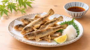 小ぶりのハゼを衣を付けずにカリッと素揚げにし、大葉、大根おろし、レモンを添えた料理写真