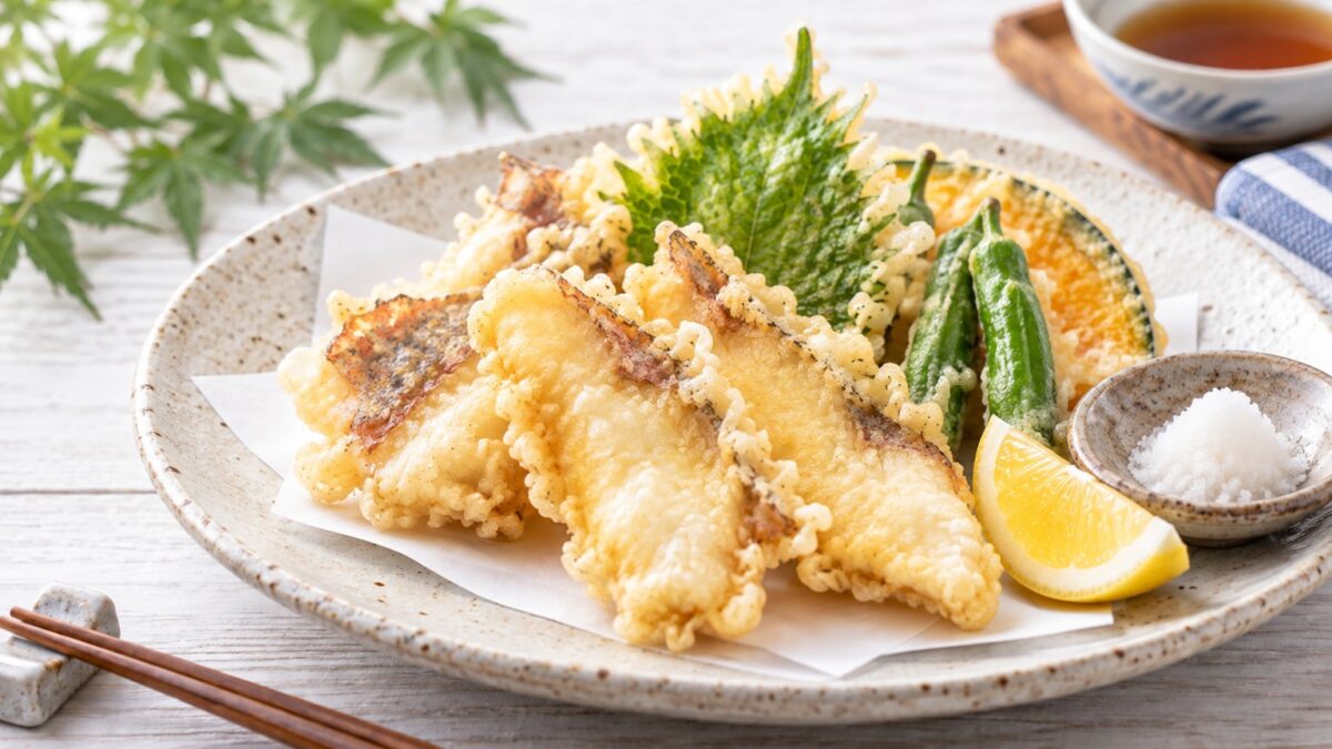 カサゴの白身の天ぷらを大葉や野菜、レモンと一緒に盛り付けた料理写真