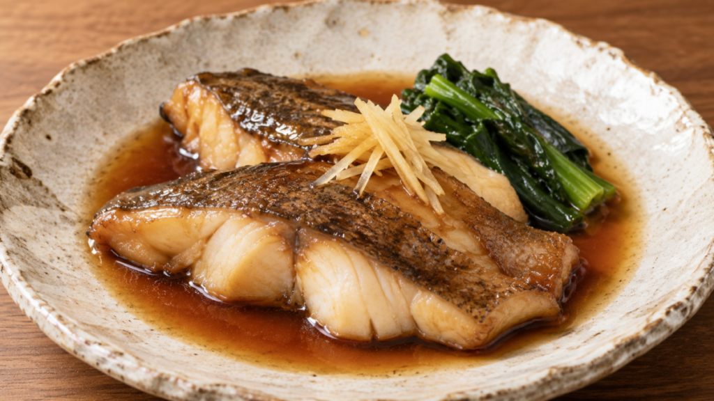 マゴチの皮付き切り身を甘辛い煮汁で煮付け、青菜と針しょうがを添えた料理写真