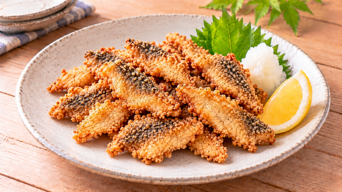 皮付きのメバルの切り身をカリッと唐揚げにし、大葉、大根おろし、レモンと盛り付けた料理写真