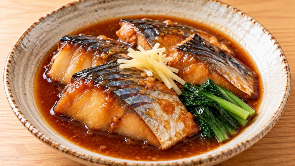 皮付きのサバの切り身を味噌だれで煮て、青菜と針しょうがを添えた味噌煮の料理写真