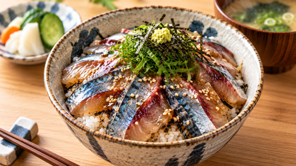 サバの漬けをご飯にのせ、大葉、刻みのり、青ねぎ、わさび、ごまを添えた漬け丼の料理写真