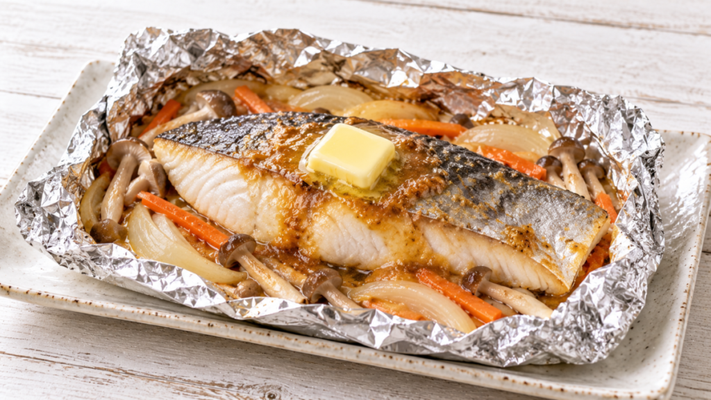 サワラの切り身を玉ねぎ、にんじん、きのこと一緒にホイルで包み、バターをのせた味噌バターホイル焼きの料理写真
