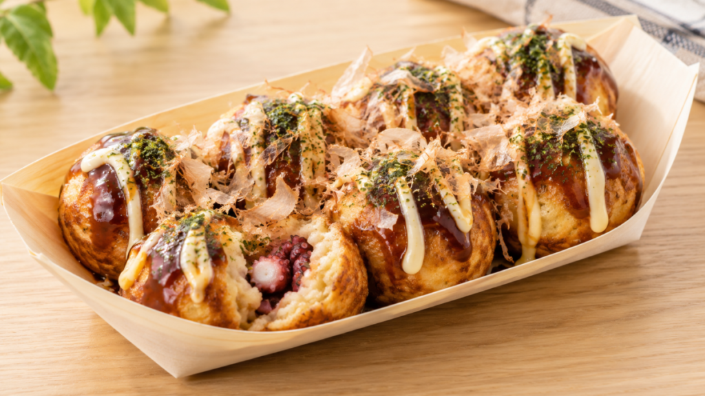 タコ入りのたこ焼きにソース、マヨネーズ、青のり、かつお節をかけて盛り付けた料理写真